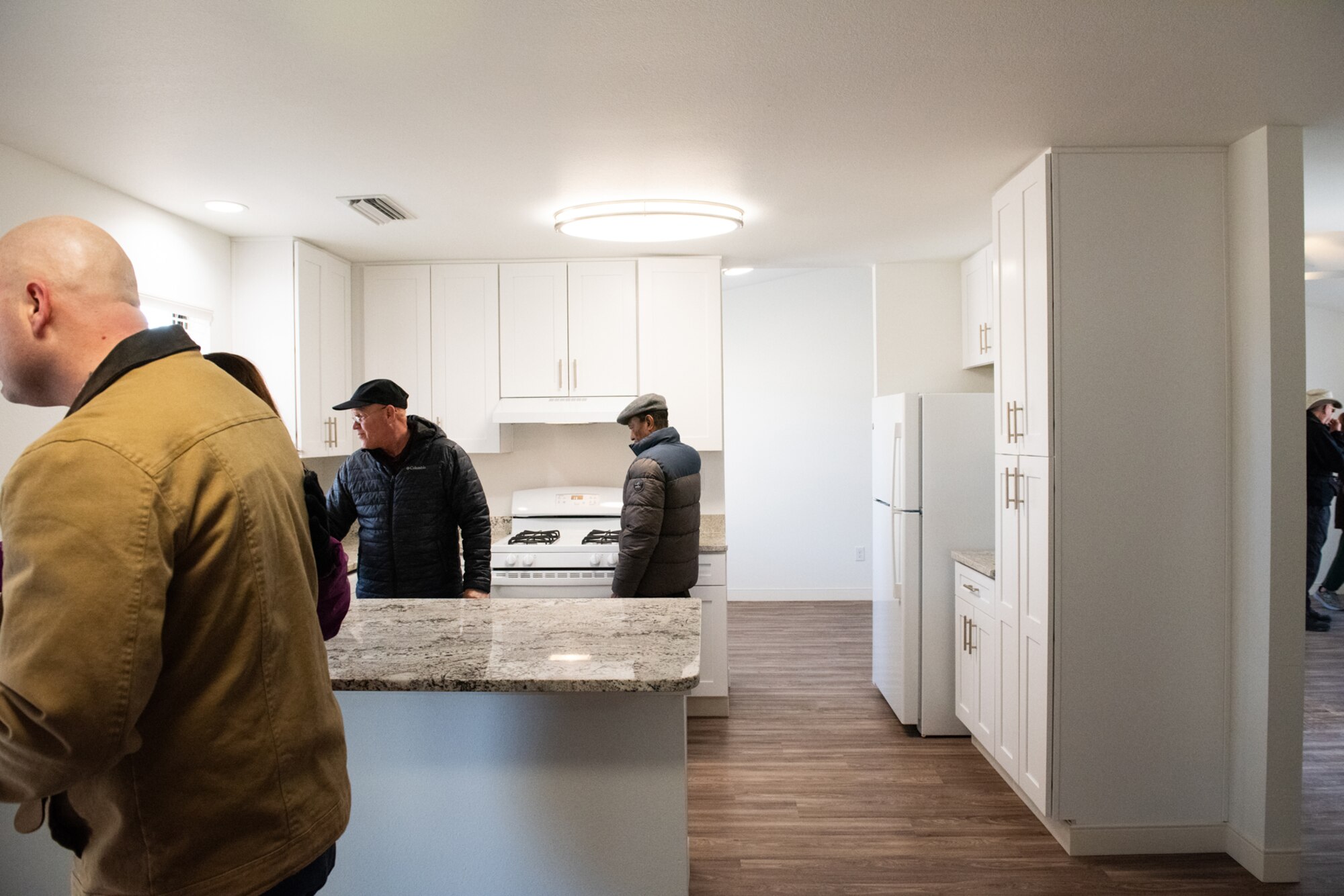 civilian men walk around kitchen in a newly renovated home