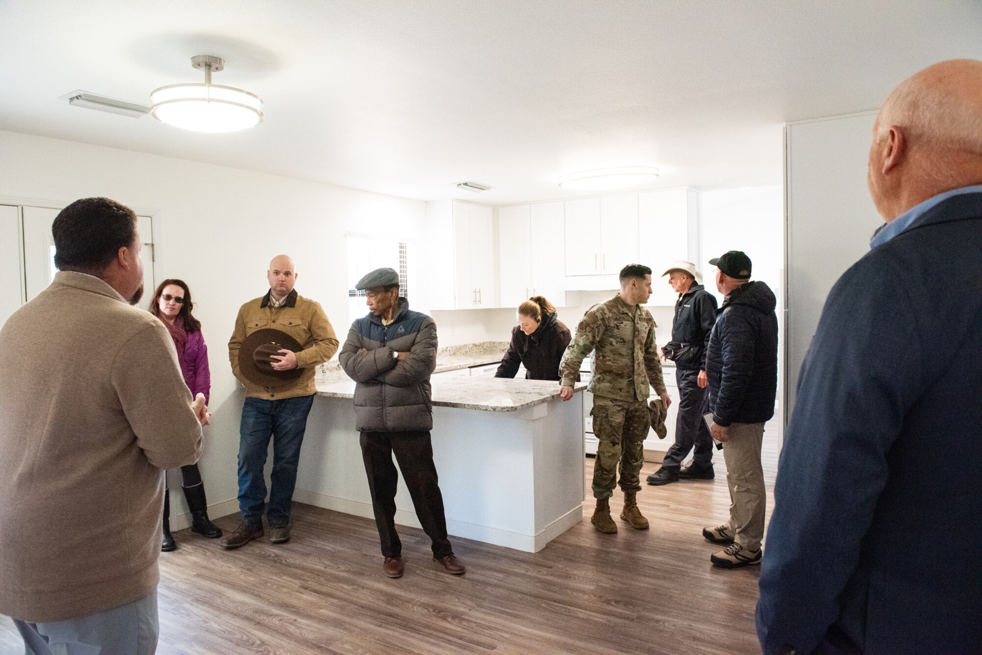 Civilians and military members stand in kitchen on newly renvovated home