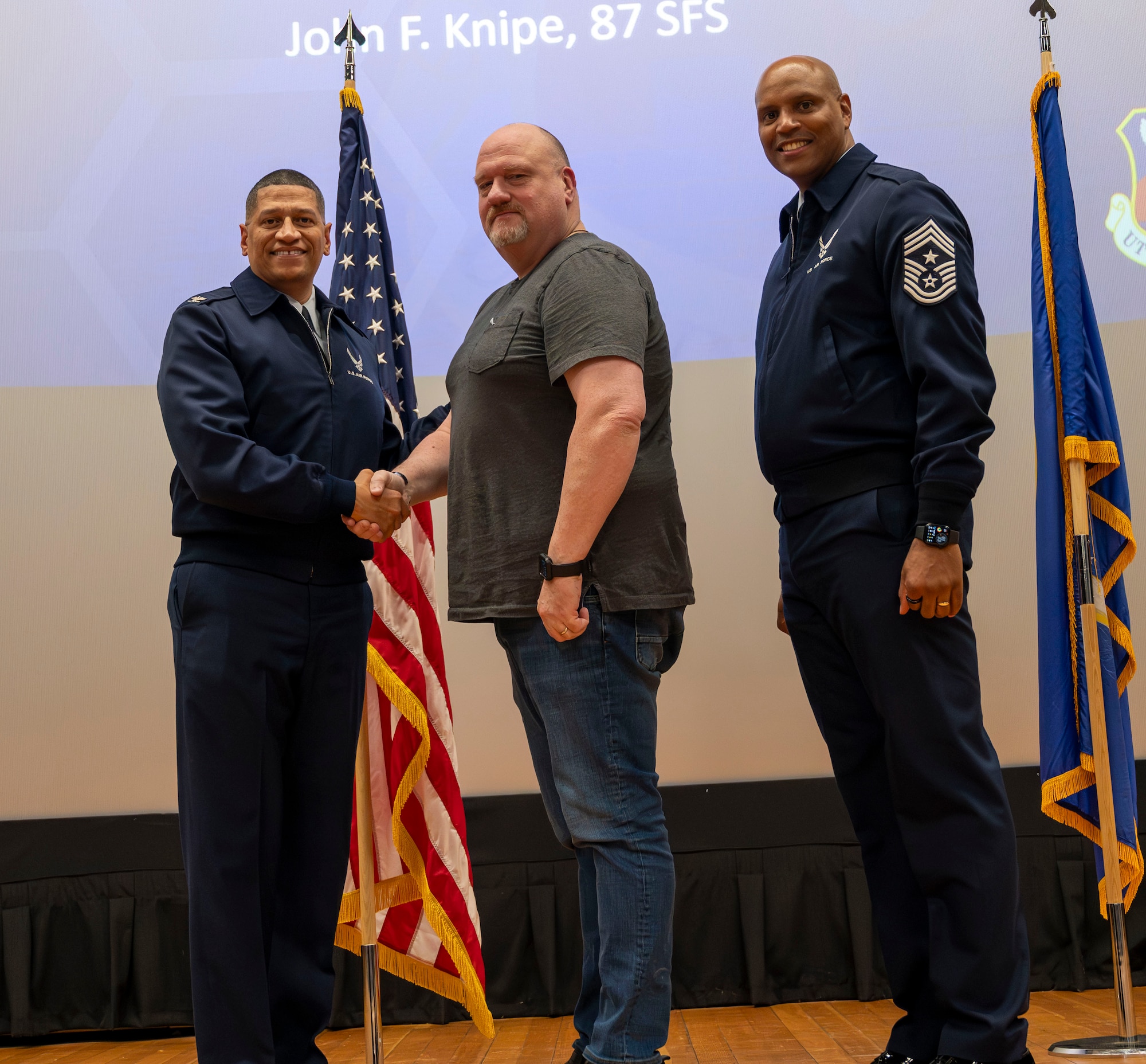 U.S. Air Force Col. Anthony L. Smith, Joint Base McGuire-Dix-Lakehurst and 87th Air Base Wing commander and Chief Master Sgt. Michael Wynne, 87th ABW command chief, recognize John Knipe, 87th Security Forces Squadron plans manager, for 30 years of government services during the 87th ABW civilian all-call at JB MDL, N.J., Jan. 23, 2025. The event provided a venue for civilian employees to receive information from the 87th ABW commander on pertinent topics, to ask questions specific to employee relations and to receive recognition. (U.S. Air Force photo by Susan Moriarty)