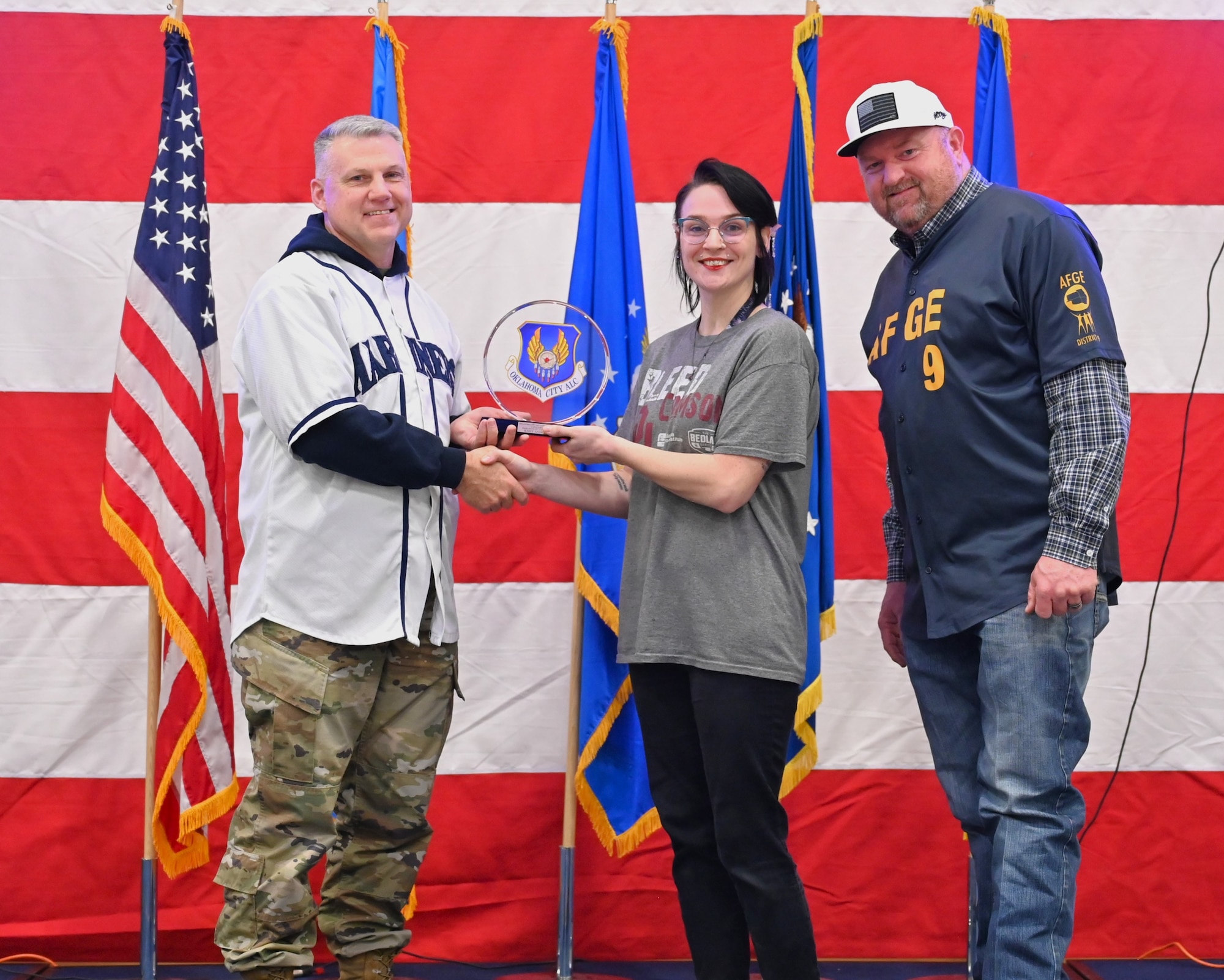 A woman in the middle of two men standing on a stage receiving an award