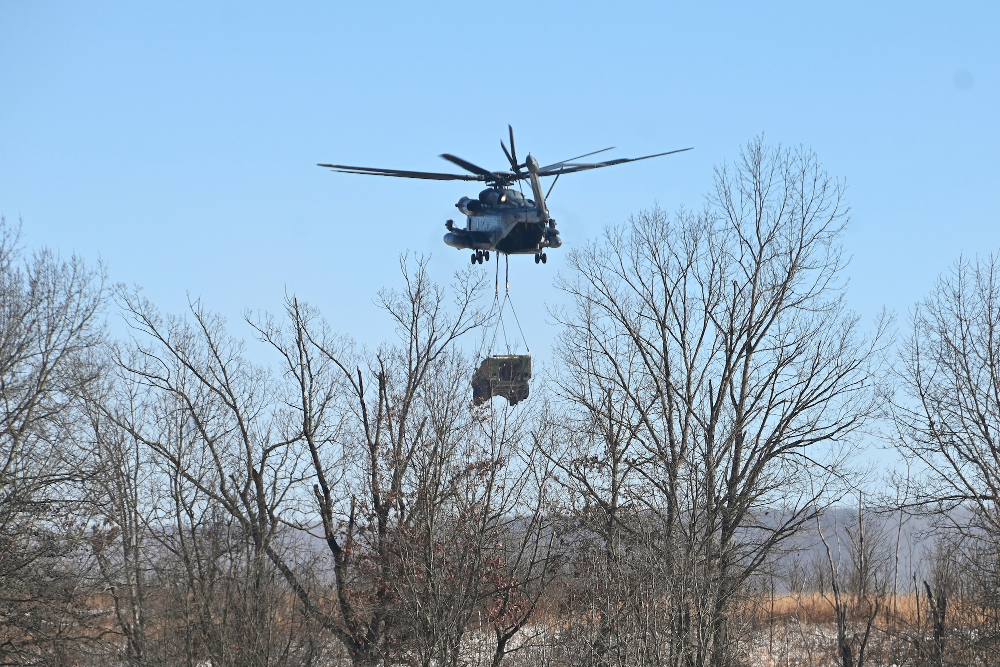 A Marine CH-53 Super Stallion helicopter from Marine Heavy Helicopter Squadron 772 out of Joint Base Maguire-Dix-Lakehurst, New Jersey, air-lifts a decommissioned Army Stryker vehicle to Fort Indiantown Gap’s impact area Jan. 22, 2025. A team of Air Force sling-load specialists from the 621st Contingency Response Group sling-loaded the Stryker to the helicopter. (Pennsylvania National Guard photo by Brad Rhen)