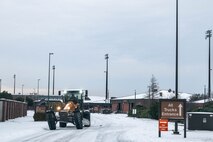 An Airman operates heavy machinery to plow snow