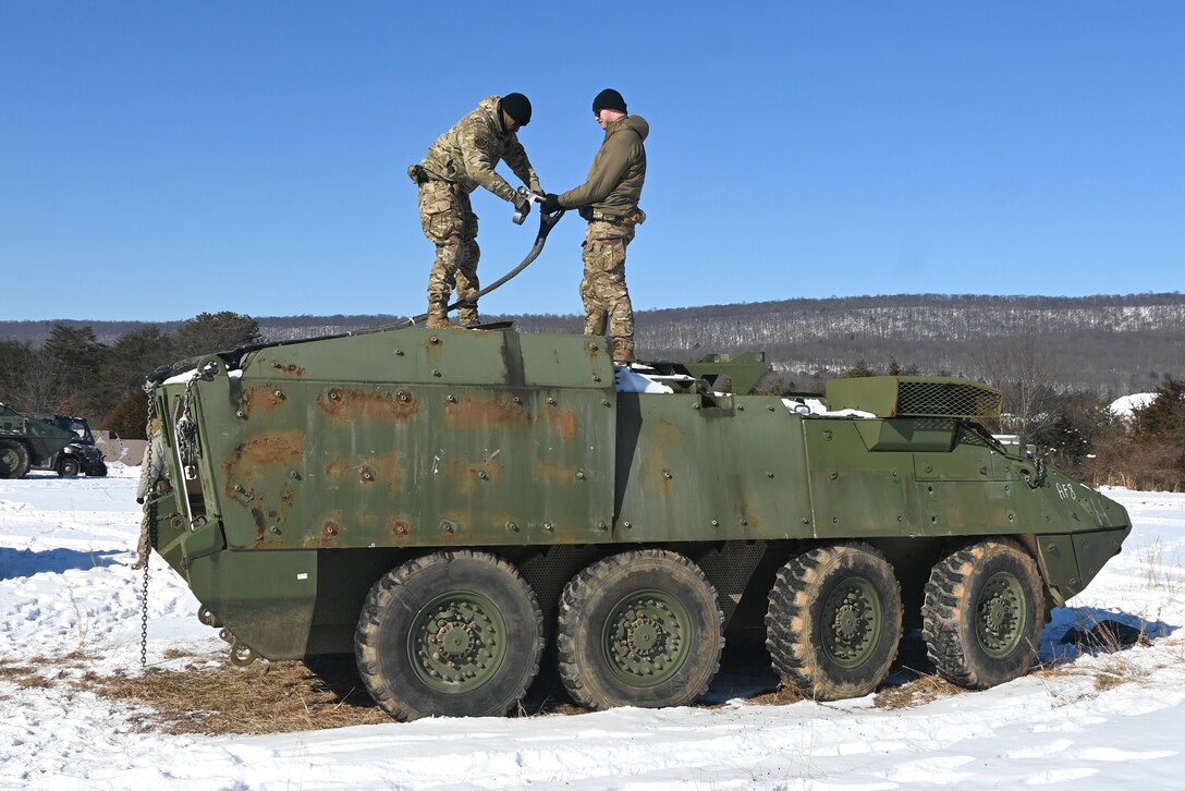 Sling-load specialists from the Air Force's 621st Contingency Response Group out of Joint Base Maguire-Dix-Lakehurst, New Jersey, prepare a decommissioned Army Stryker vehicle to be air-lifted to Fort Indiantown Gap’s impact area Jan. 22, 2025. A Marine CH-53 Super Stallion helicopter from Marine Heavy Helicopter Squadron 772 air-lifted eight Strykers to the impact area where they will be used as targets. (Pennsylvania National Guard photo by Brad Rhen)