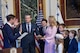 Two men hold up their right hands at ceremony while family members look on.