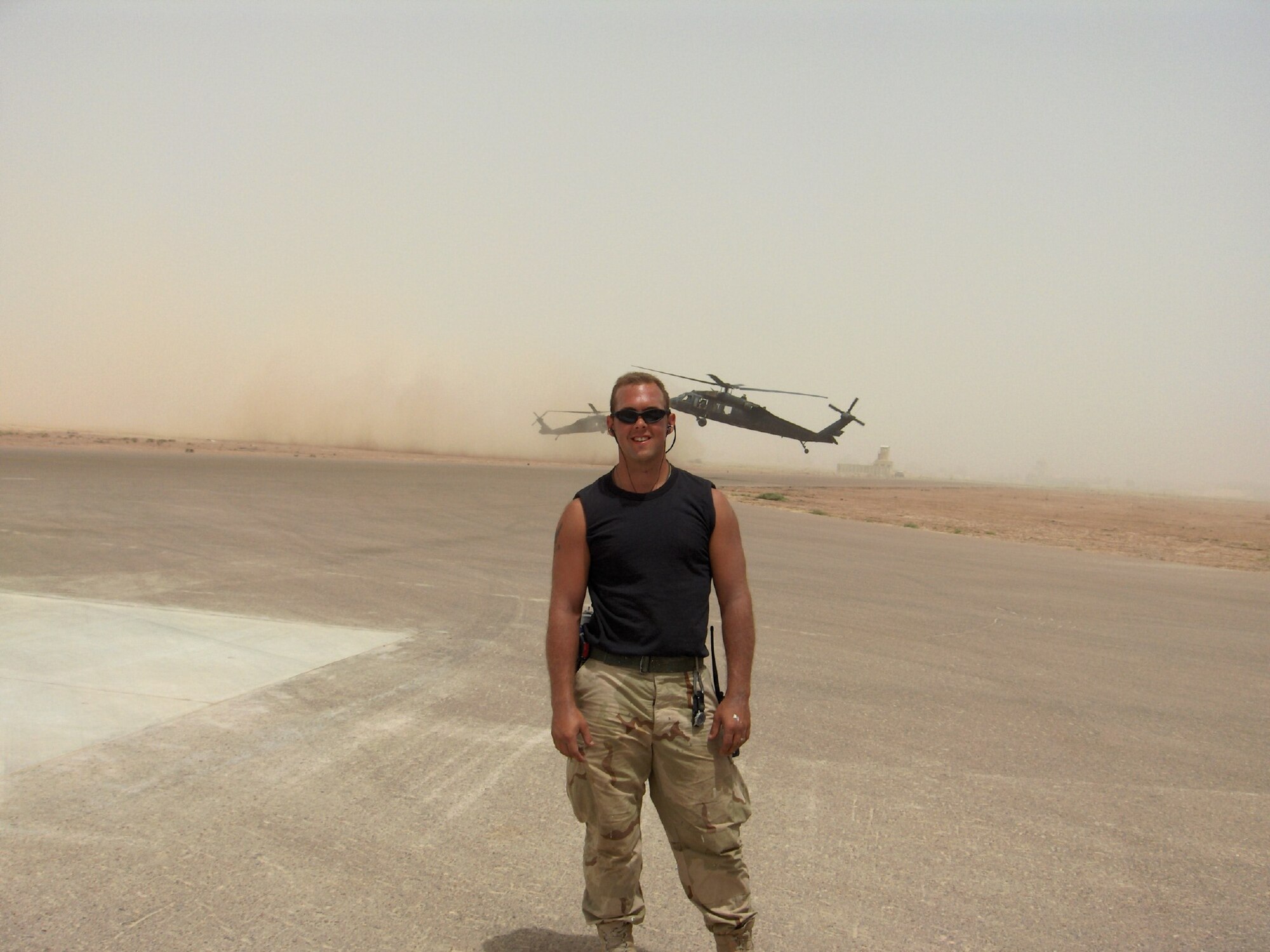 US. Air Force 325th Fighter Wing Command Chief Luke Lucas stands on an air field during deployment with two helicopters behind him