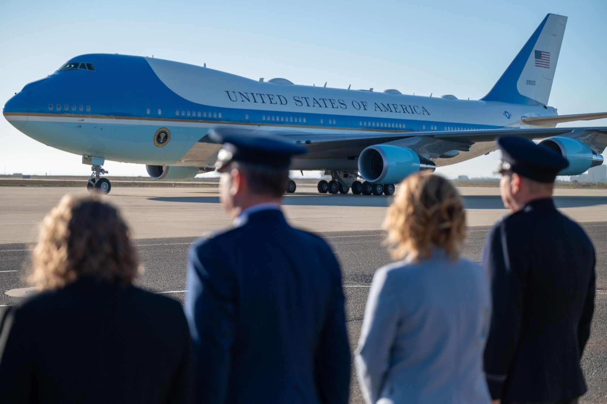 People stand along the flightline with air force one in the background.