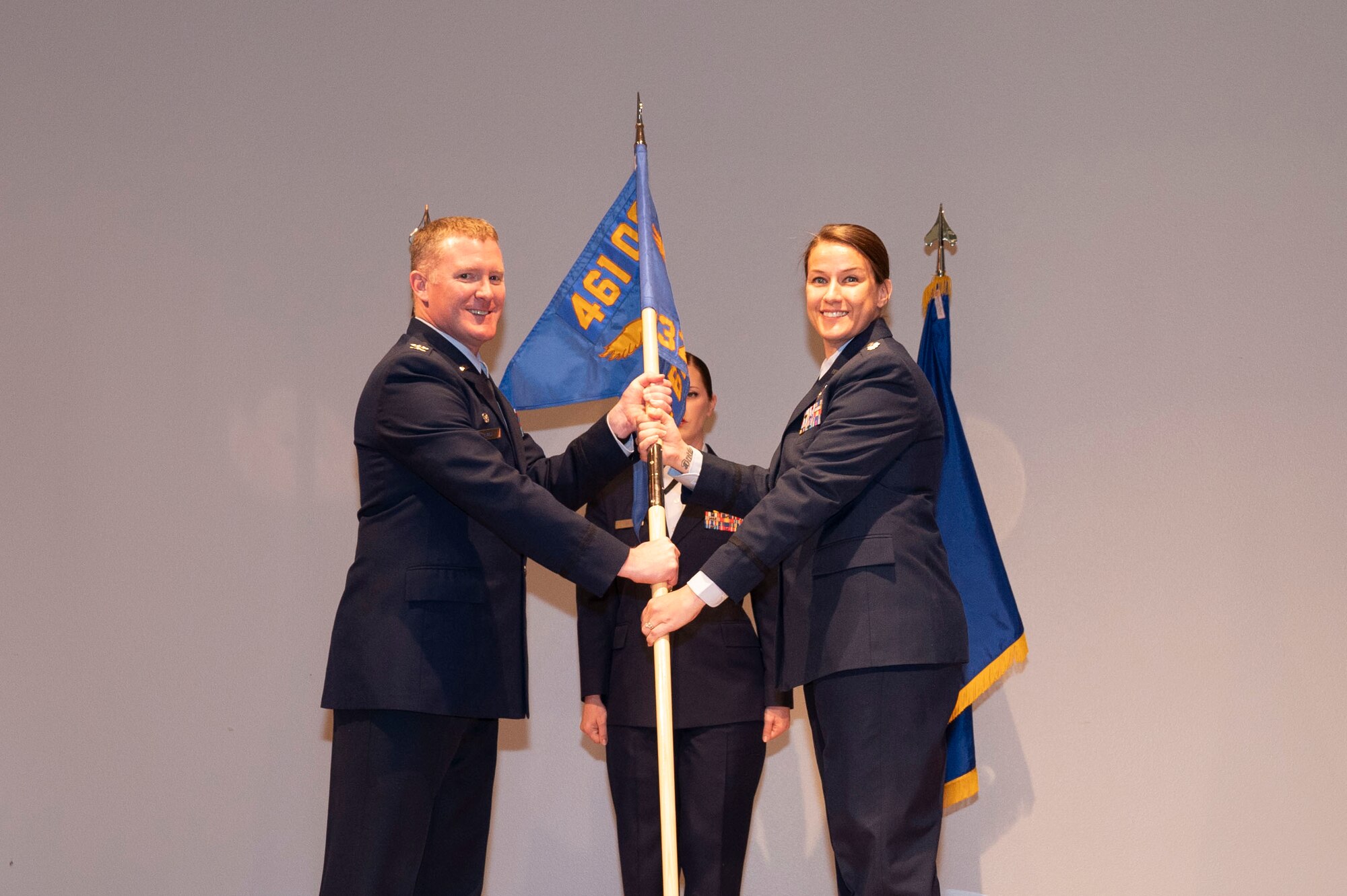 U.S. Air Force Col. Michael Lynch, 461st Operations Group commander, and Lt. Col. Nicole Ketron, 932nd Battle Management Control Squadron (BMCS) commander unfurl and present the 932nd BMCS guidon during the 932nd BMCS activation and assumption of command ceremony in the Community Activity Center at Beale Air Force Base, California, Jan 23, 2025.