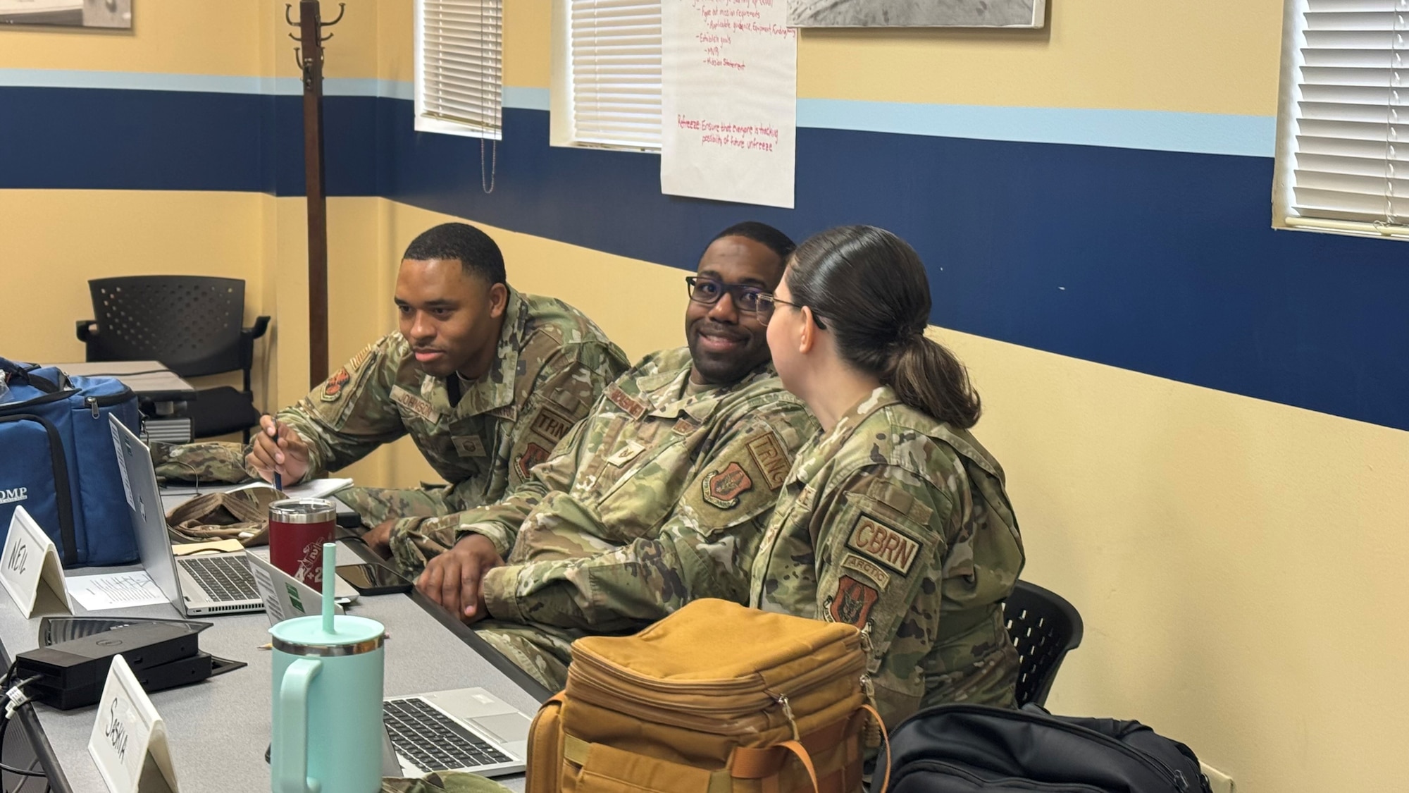U.S. Air Force Master Sgt. Daniel Johnson left, 908th Maintenance Group, Tech. Sgt. Torrence Washington, 908th Flying Training Wing, and Master Sgt. Sasha Harrison, 908th Civil Engineering Squadron, all Foundations 700 Course students, speak to each other in the classroom at Maxwell Air Force Base, Alabama, Dec. 19, 2025.