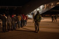 Agents guide illegal aliens onboard an aircraft.