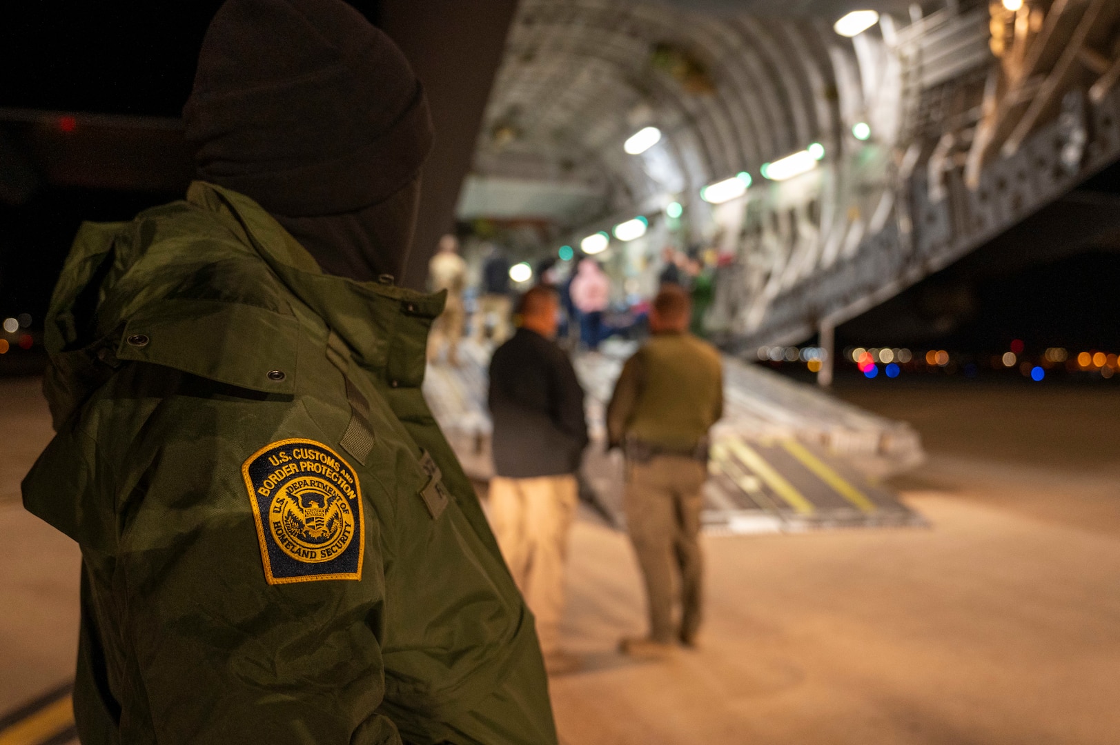An agent watches as illegal aliens are loaded onto an aircraft.