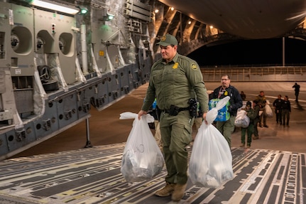 Agents load water bottles and illegal aliens' personal belongings onto an aircraft.
