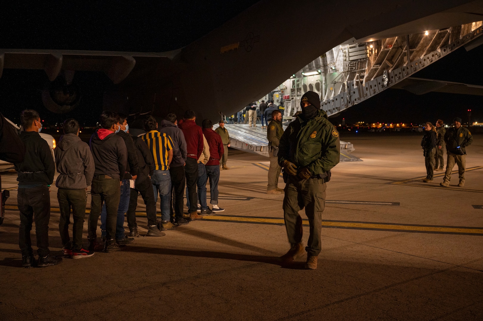Agents guide illegal aliens onboard an aircraft.