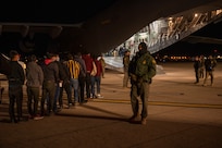 Agents guide illegal aliens onboard an aircraft.
