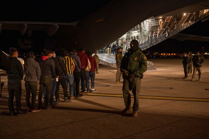 Agents guide illegal aliens onboard an aircraft.