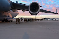 Soldiers exit an aircraft.