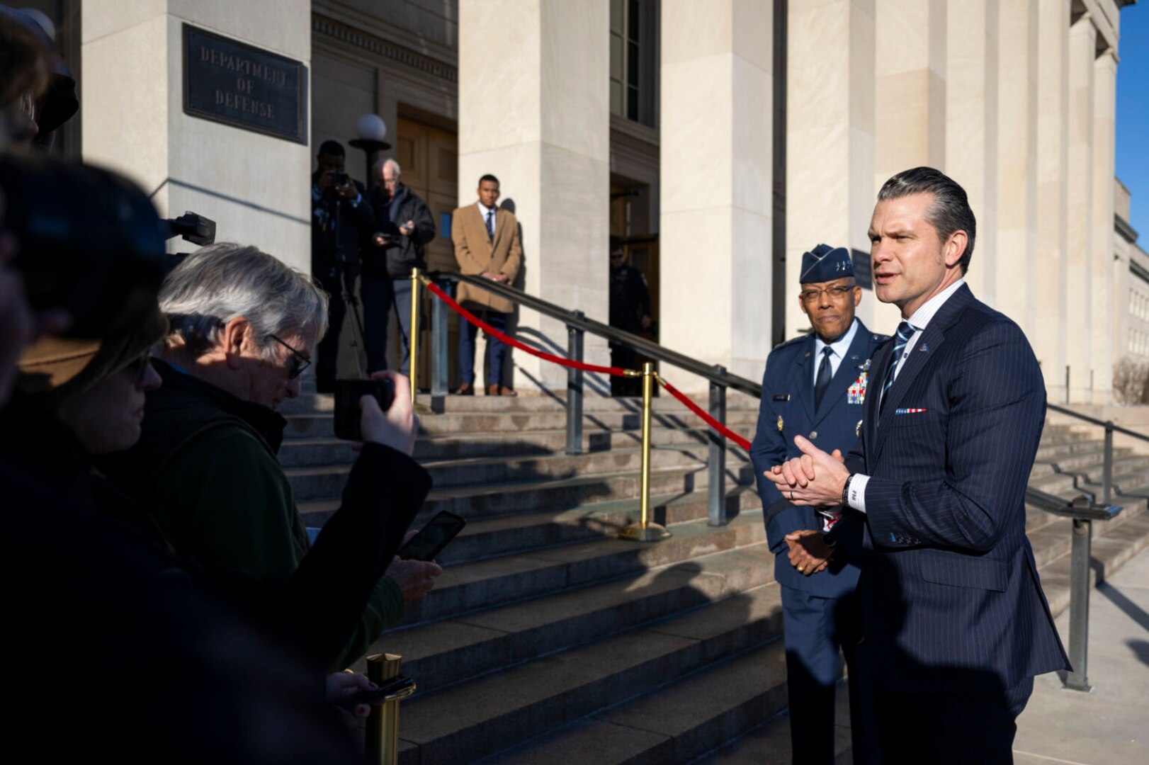 A man wearing business attire speaks to the press on the steps of the Pentagon.