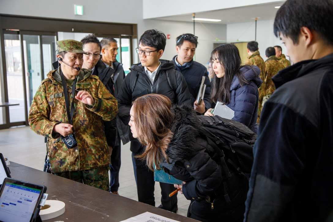 A Japan Ground Self-Defense Force member with the 13th Brigade, Middle Army, explains evacuee processing to U.S. and Japanese government officials at the Lotus Cultural Center during Exercise Nankai Rescue, in Iwakuni, Japan, Jan. 16, 2025. Exercise Nankai Rescue 2024 is a full-scale exercise focused on enhancing bilateral coordination between the U.S. and Japan in support of humanitarian and disaster relief efforts. (U.S. Marine Corps photo by Sgt. Randall Whiteman)