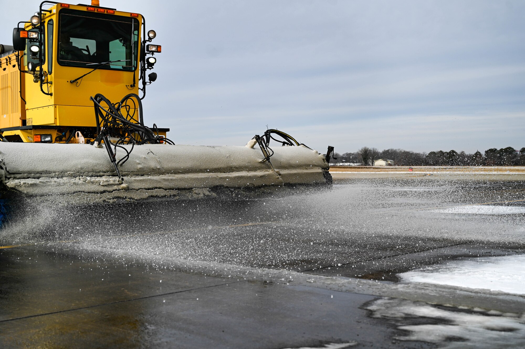 Truck with a snow broom breaking up snow and ice on a flightline