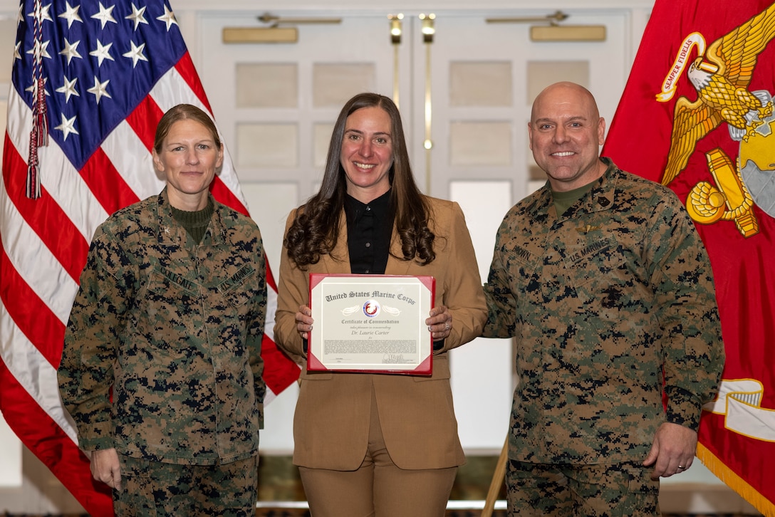Dr. Laurie Carter, director of the Substance Abuse Counseling Program, Behavioral Health Branch, Marine Corps Community Services, poses with U.S. Marine Corps Col. Jenny Colegate, commanding officer of Marine Corps Base Quantico, left, and Sgt. Maj. Michael R. Brown, sergeant major of MCBQ, during the Civilian Quarterly Awards at The Clubs at Quantico, MCBQ, Virginia, January 23, 2025. Carter was recognized as the Senior Non-Appropriated Fund Personnel Civilian Employee of the Year for work done in 2024. (U.S. Marine Corps photo by Lance Cpl. David Brandes)
