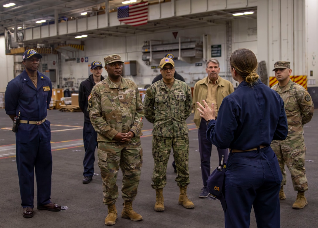 A Navy sailor briefs distinguished while aboard a carrier.