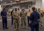 A Navy sailor briefs distinguished while aboard a carrier.