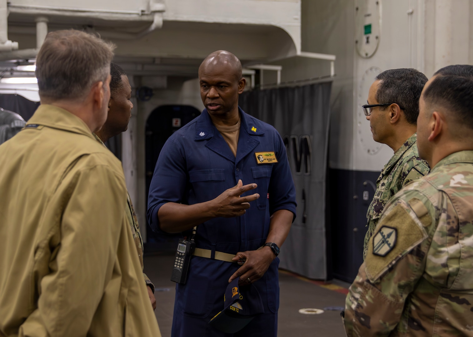 Navy sailor briefs three people.