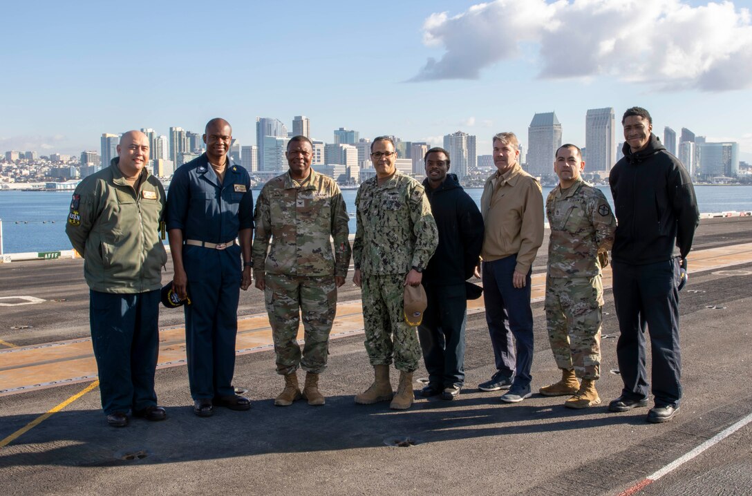 Eight people pose for a photo on USS Abraham Lincoln
