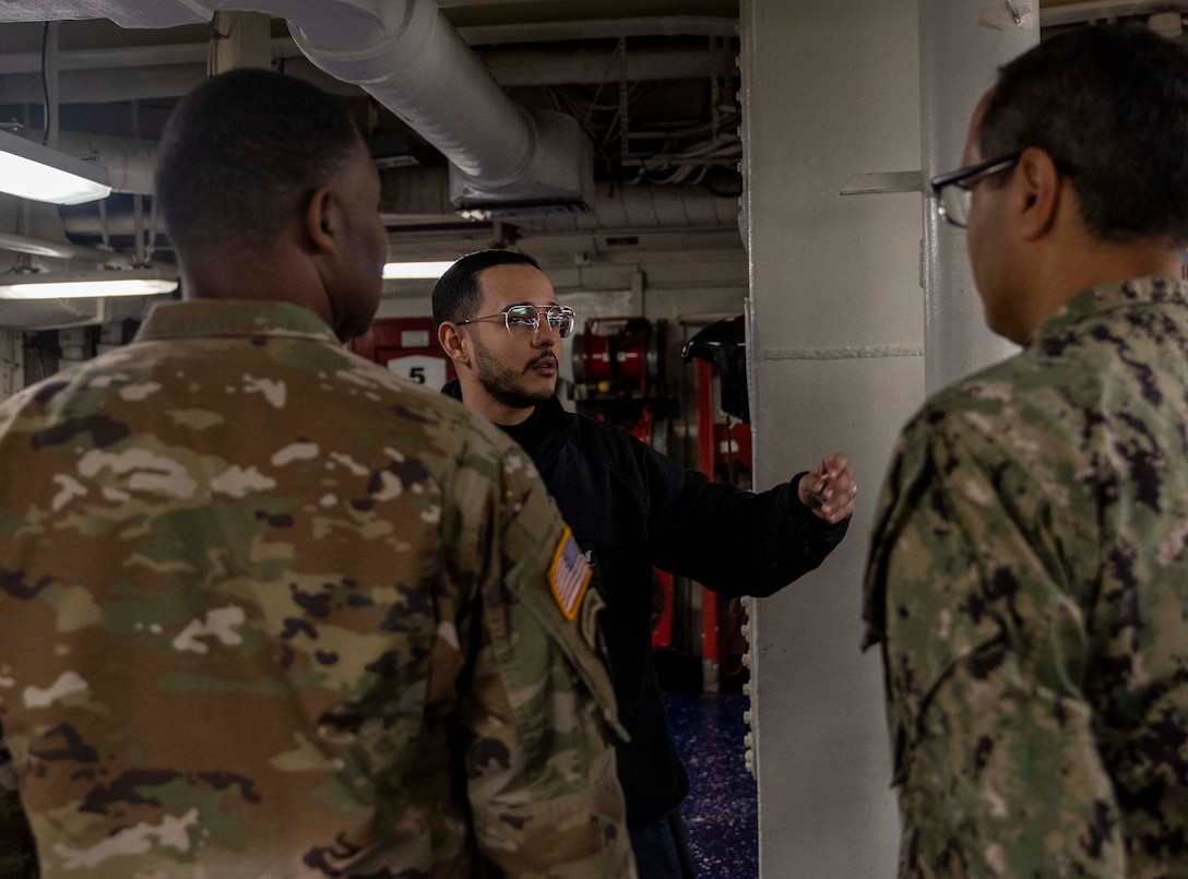 Two people receives brief from Navy sailor