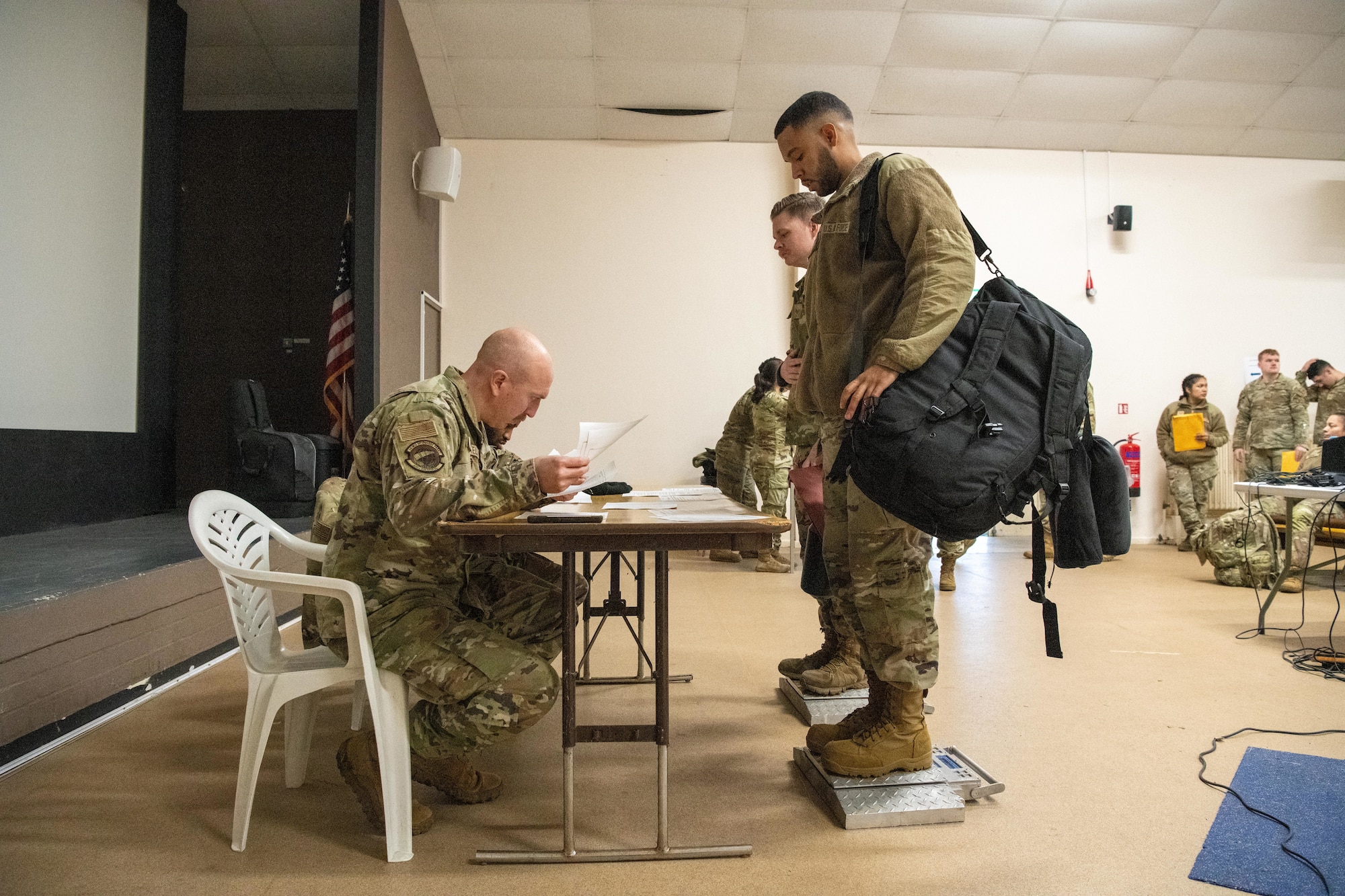 Airmen stand on portable wheel loader scales