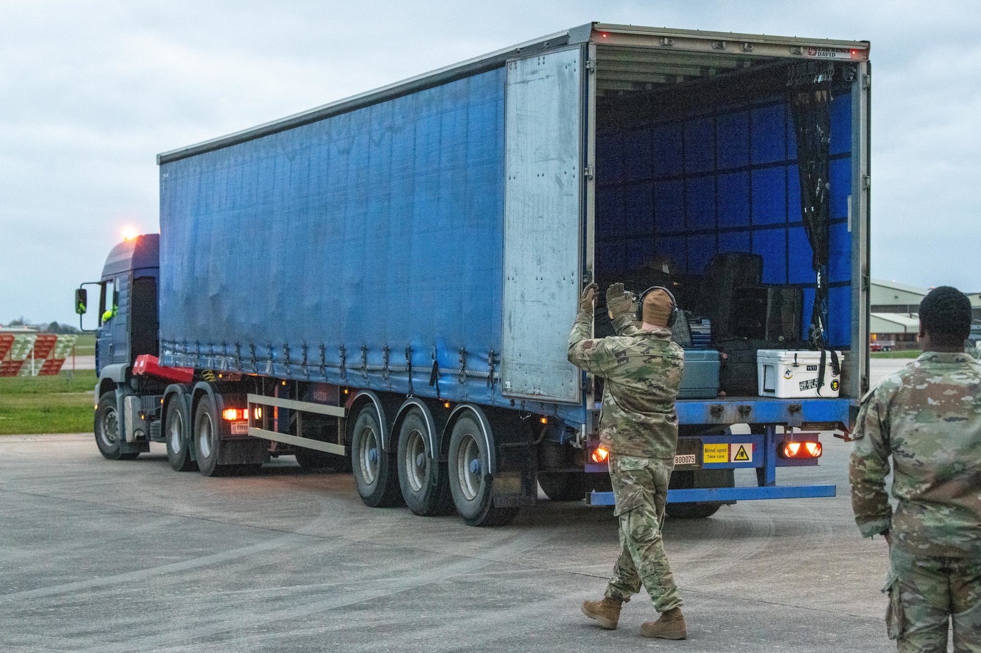 Airman guides a freight truck to a baggage conveyor