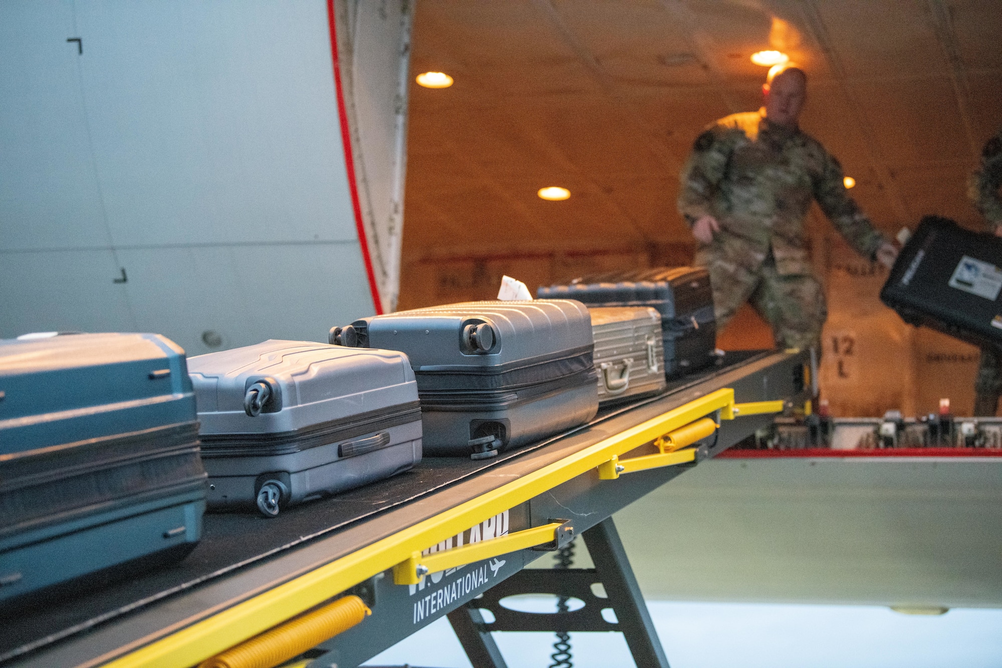 Airman onloads luggage aboard an Omni Air International 777 aircraft