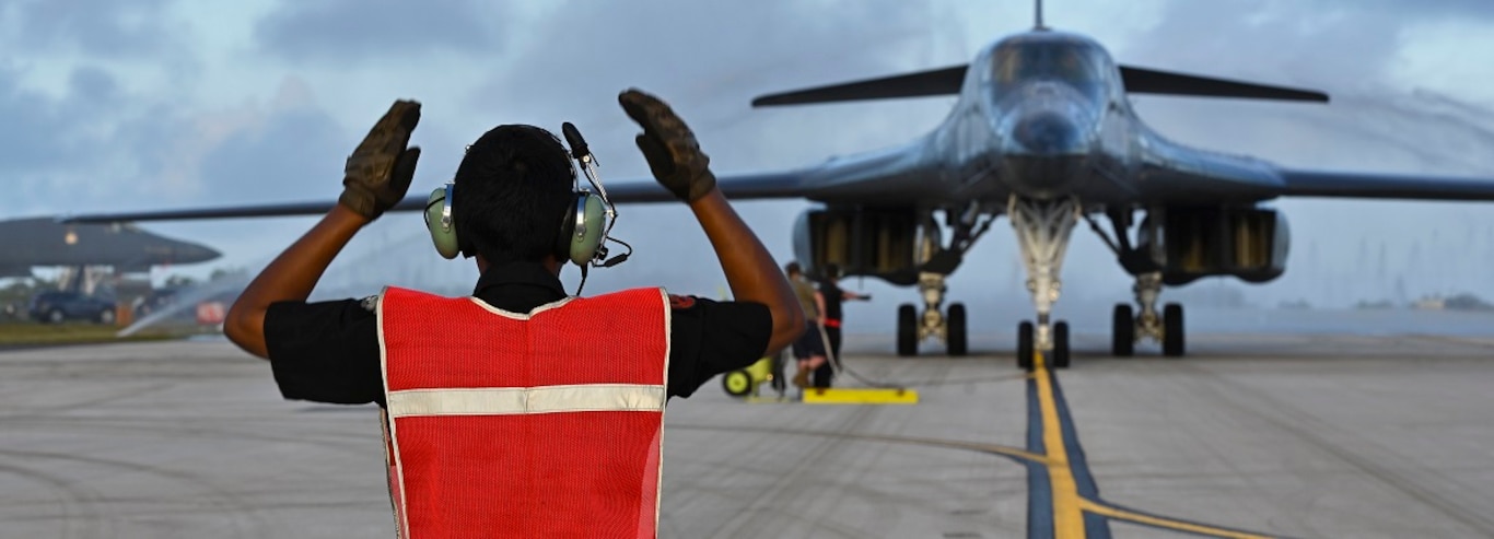 U.S. Air Force Senior Airman Andre Monterrosa, 34th Expeditionary Bomb Squadron assistant dedicated crew chief, marshals a B-1B Lancer through a clear water rinse at Andersen Air Force Base, Guam, Jan. 27, 2025.