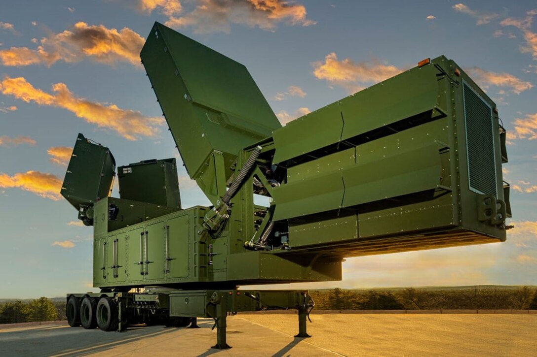 An air defense system stands under a blue sky on concrete.
