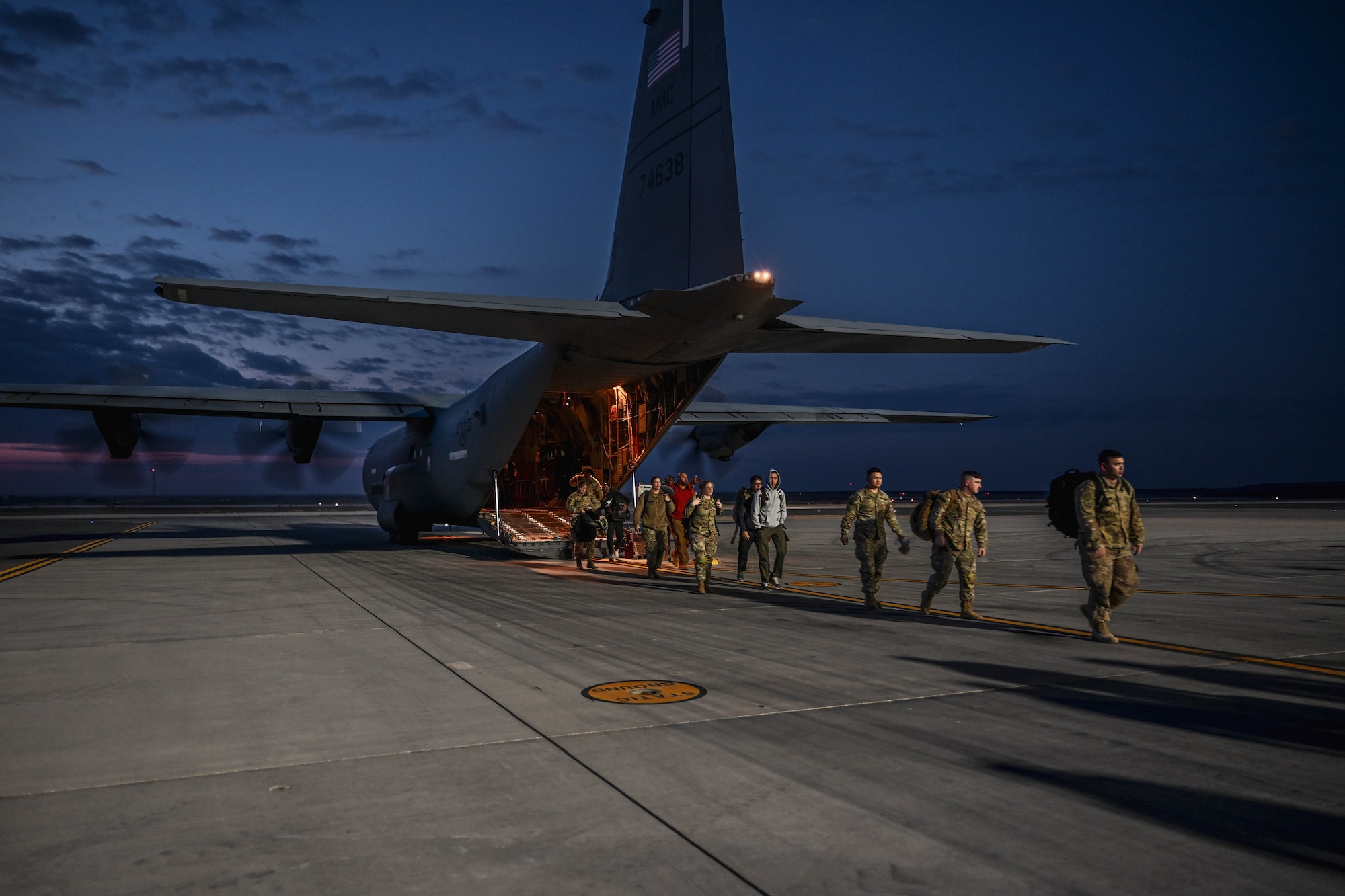 Military members in uniform offload from a C-130J Super Hercules.
