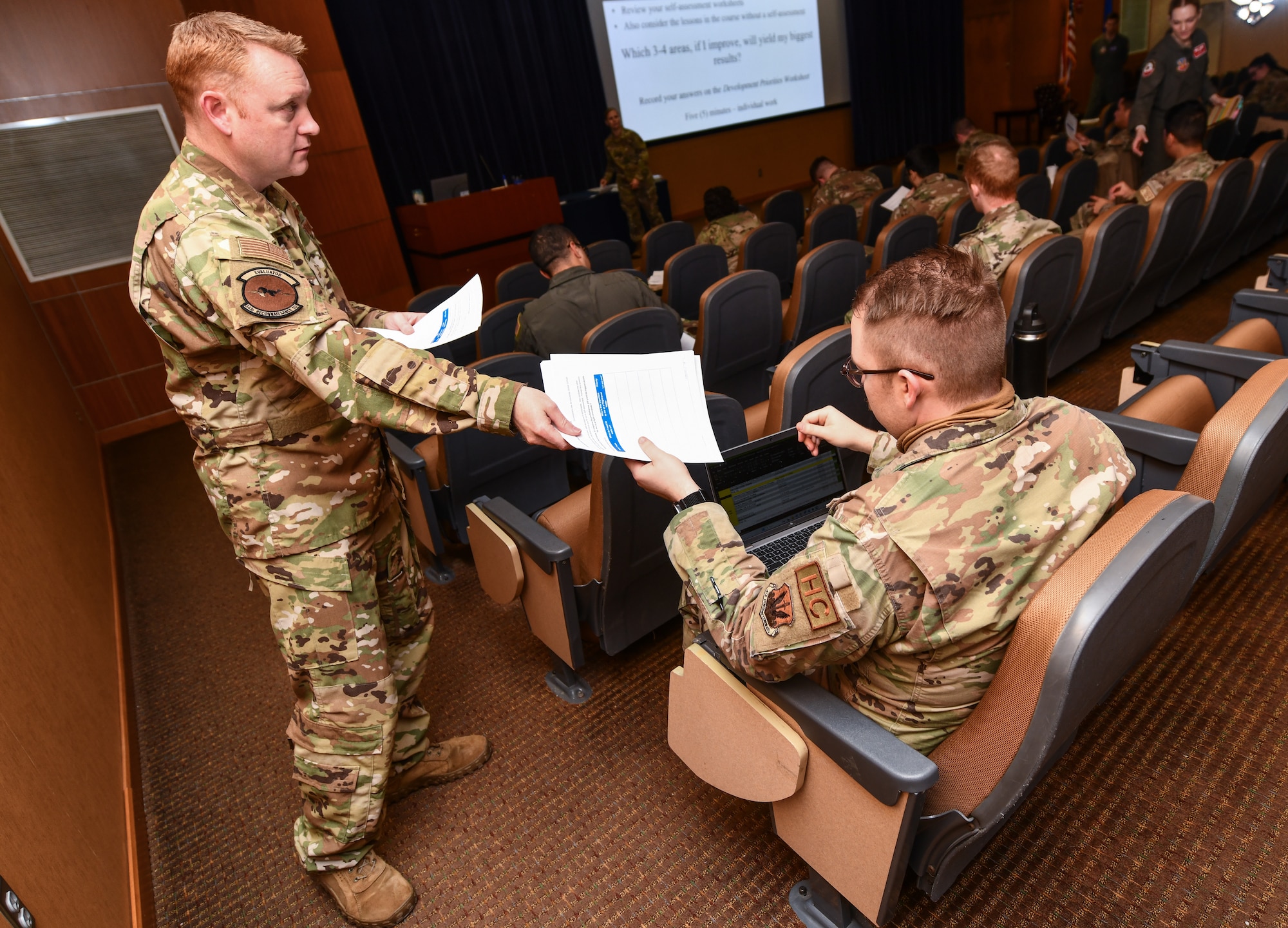 Master Sgt. Nathan Schiers, 343rd Reconnaissance Squadron, hands a worksheet to Capt. Zachary Bennett, 55th Wing chaplain, at the Flight Commanders Course on Offutt Air Force Base, Jan. 24, 2025. (U.S. Air Force photo by Chad Watkins)