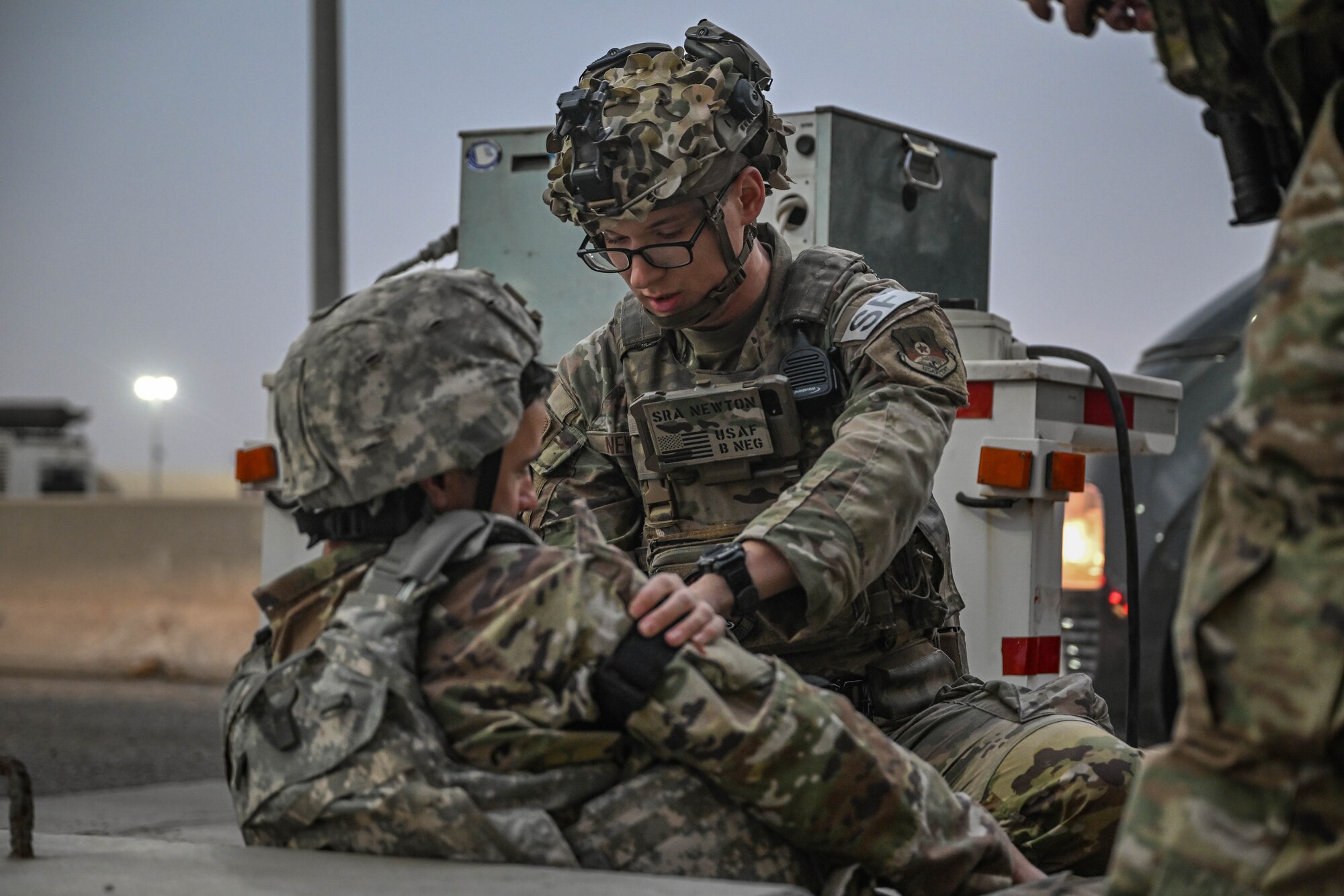 A man in uniform performs first aid on a simulated casualty during an exercise.