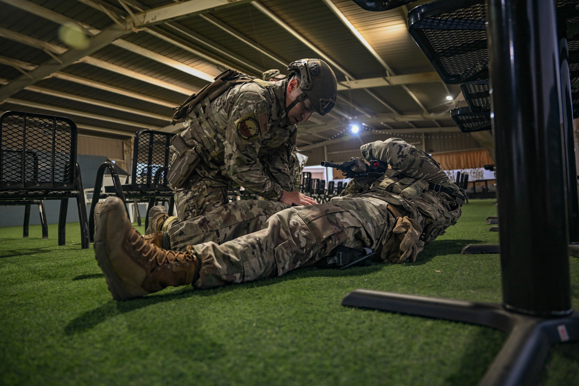 A man in uniform practices first aid on a simulated casualty.