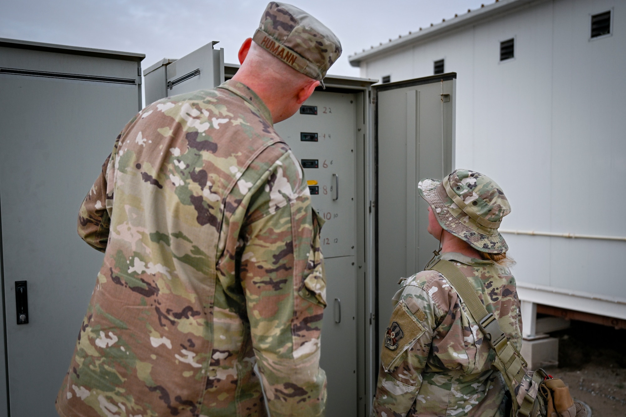 Two U.S. Air Force Airmen look at a lift station panel.