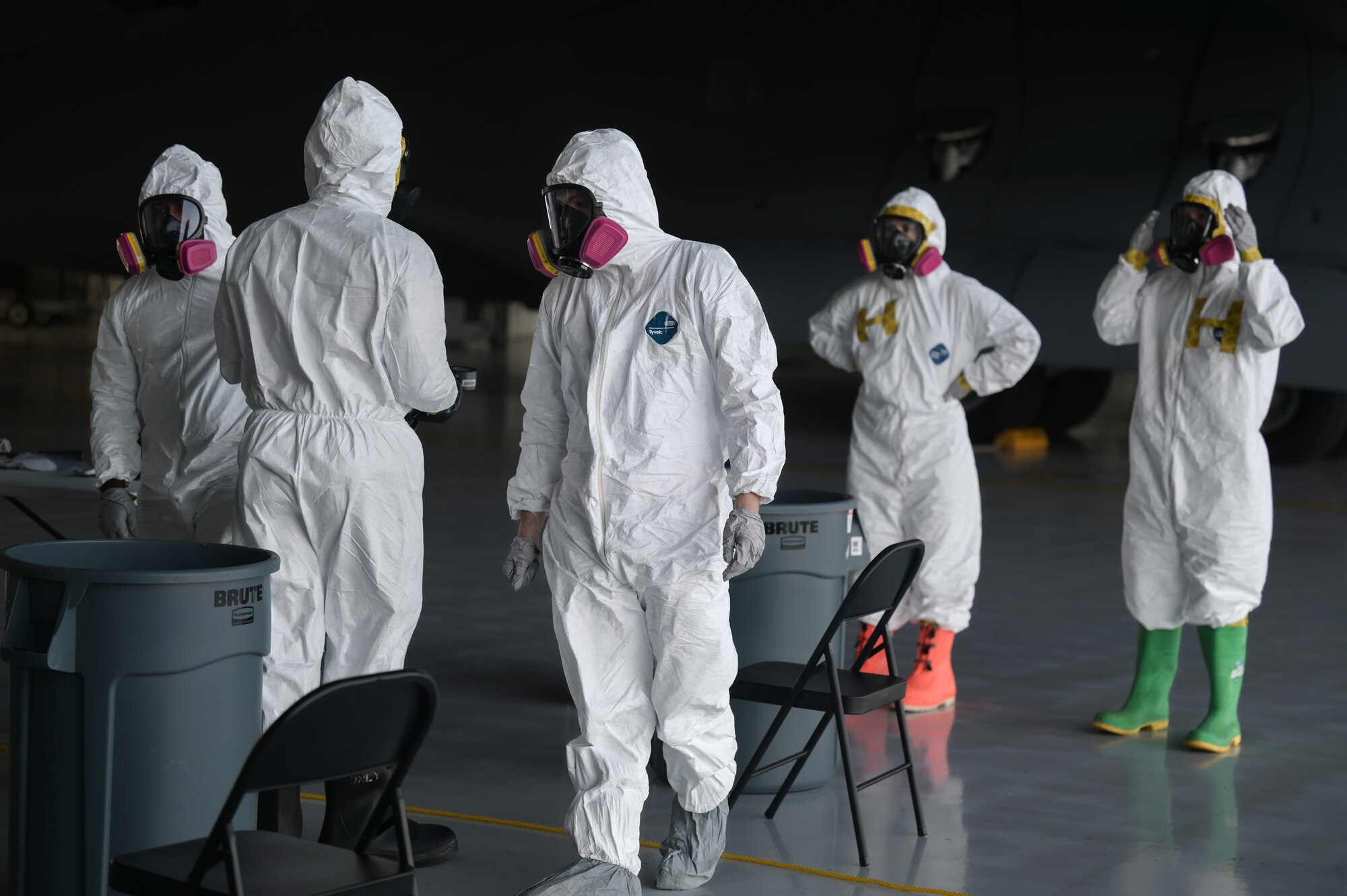 Airmen grouped together use chemical detection equipment while wearing chemical protection gear.