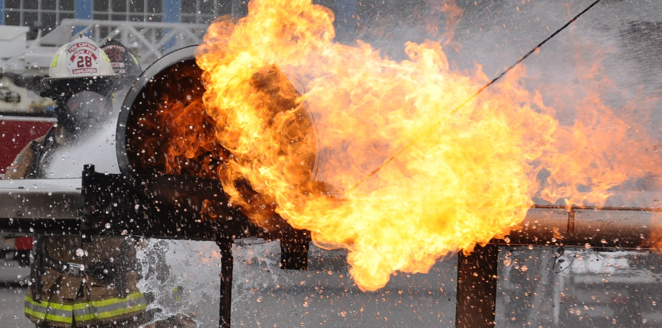 Fire meets water: firefighters assigned to Naval Support Facility Dahlgren address a fire on a simulated aircraft engine of the Mobile Aircraft Firefighting Training Device (MAFTD), during annual live-fire training May 2.