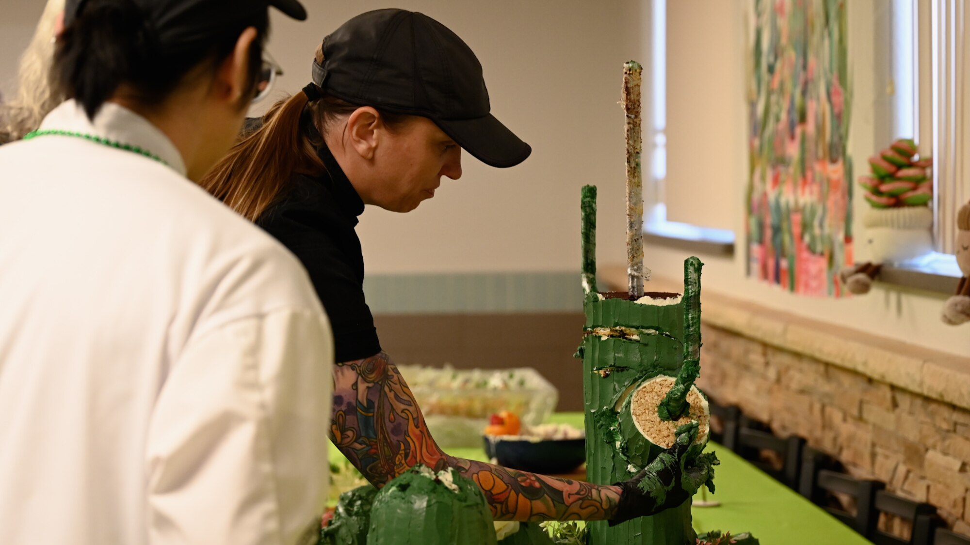 Sarah Lamberth, 355th Force Support Squadron executive chef, cuts the cactus cake to symbolize the start of the John L. Hennessy inspection at Davis-Monthan Air Force Base, Arizona, Jan. 26, 2025. The trophy is named after John L. Hennessy, a leader in the hospitality industry who contributed to improving military food service standards. (U.S. Air Force photo by Senior Airman Andrew Garavito)