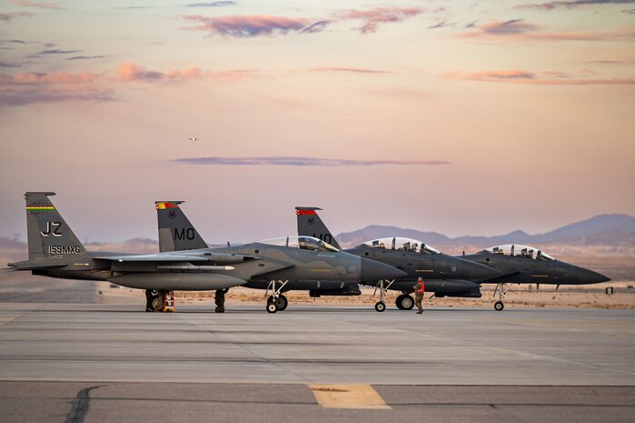 An F-15C Eagle (left) assigned to the 159th Fighter Wing, Louisiana Air National Guard, Naval Air Station Joint Reserve Base New Orleans, Louisiana, parks next to two F-15E Strike Eagles assigned to 366th Fighter Wing, Mountain Home Air Force Base (AFB), Idaho, taxi in after a mission during Red Flag-Nellis 25-1, Jan. 27, 2025, at Nellis AFB, Nevada.