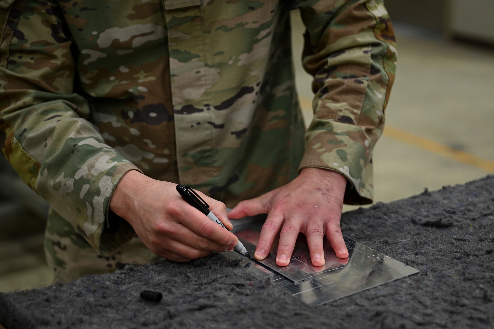 U.S. Air Force Tech. Sgt. Timothy Abian, 8th Maintenance Squadron aircraft structural maintenance section chief, marks lines on sheet metal at Kunsan Air Base, Republic of Korea.