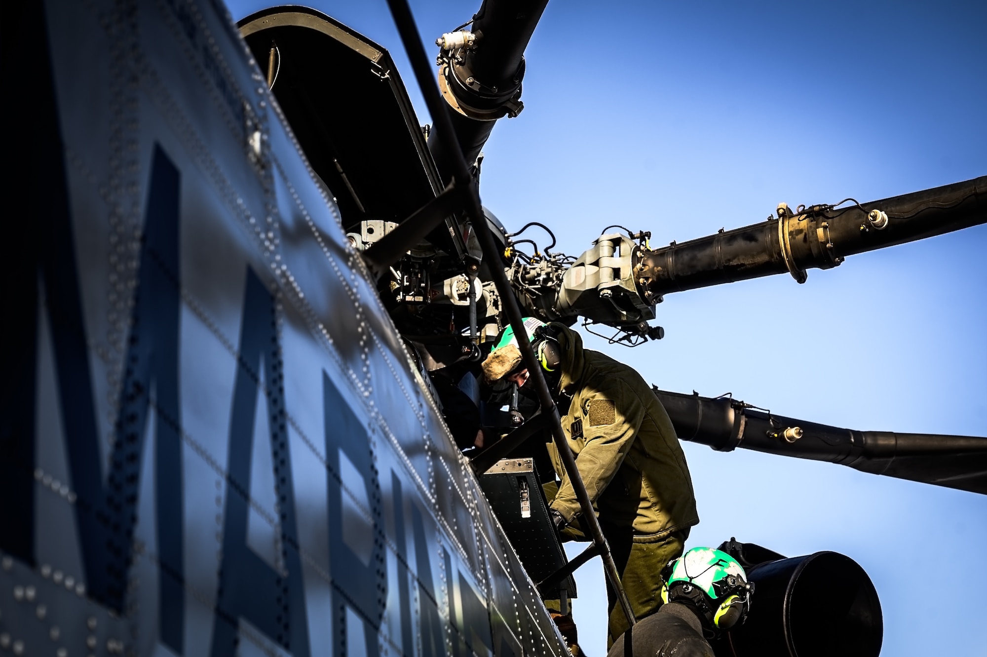 U.S. Marine Corps Cpls. Ryan Ewing and Juan Estrada, Marine Heavy Helicopter Squadron 772 helicopter crew chiefs, perform a maintenance check on a CH-53E Super Stallion helicopter before takeoff at Joint Base McGuire-Dix-Lakehurst, N.J., Jan. 22, 2025. The helicopter was requested on behalf of the Pennsylvania Army National Guard to lift and relocate nine Stryker armored vehicles to the Fort Indiantown Gap training range. The lift was assisted by a team of U.S. Air Force Airmen assigned to the 621st Contingency Response Group who secured and released each Stryker to the helicopter. (U.S. Air Force photo by Senior Airman Matt Porter)