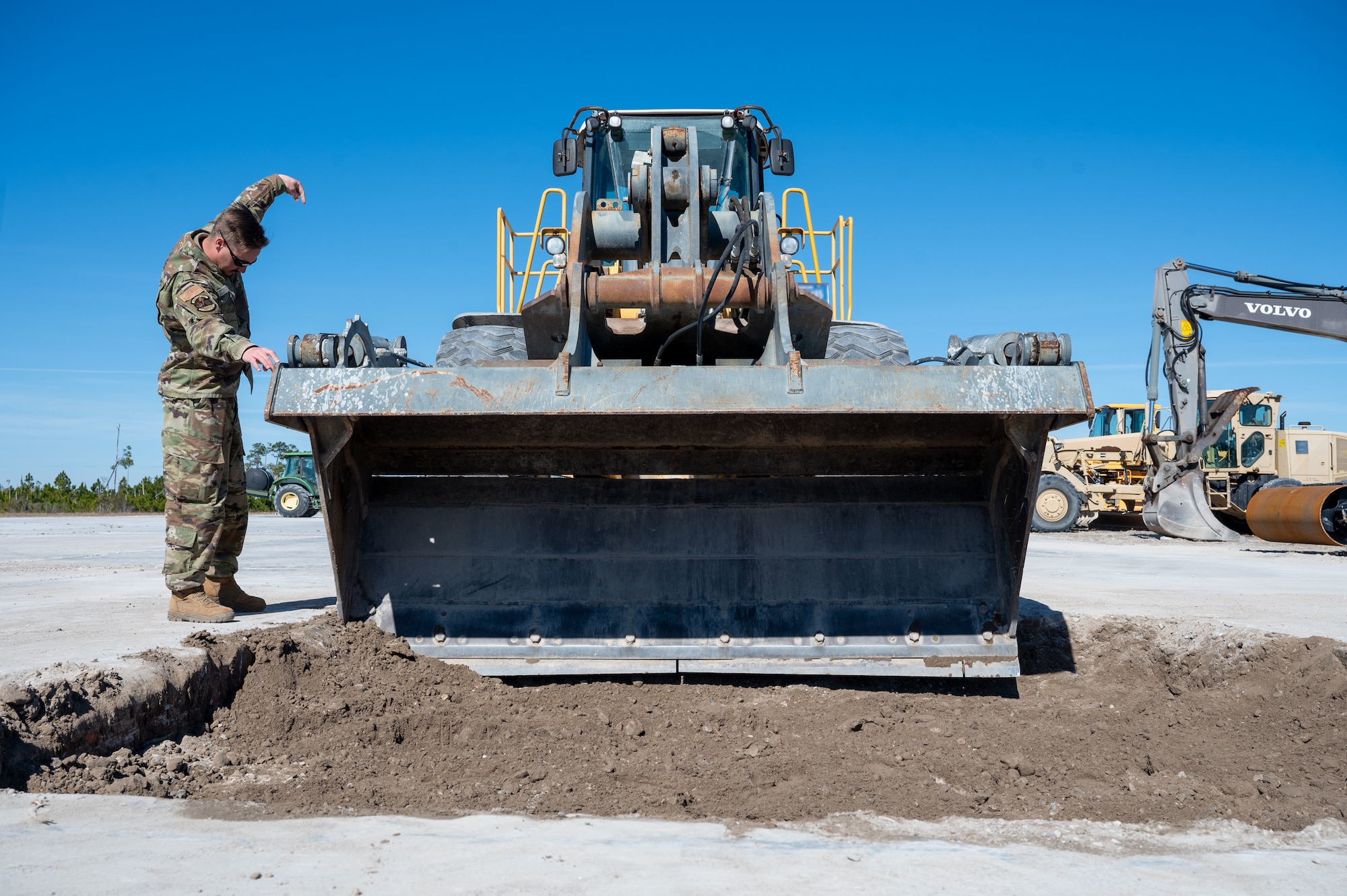 A U.S. Airman assigned to the 11th Air Task Force guides a heavy construction vehicle at Tyndall Air Force Base, Florida, Jan. 26, 2025. Airmen performed crater repair on a flight line damaged during a simulated severe weather event. (U.S. Air Force photo by Senior Airman Jasmyne Bridgers-Matos)