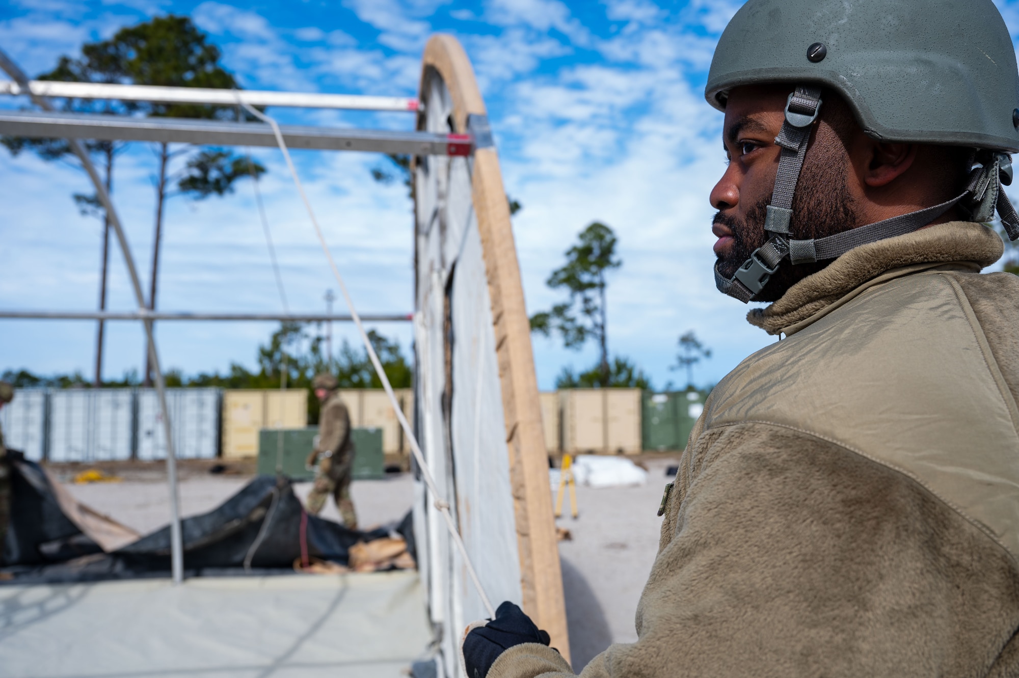 A U.S. Airman assigned to the 11th Air Task Force hoists the side panel of a tent into place at Tyndall Air Force Base, Florida, Jan. 21, 2025. The 11th ATF generates a team of mission ready Airmen for the joint force to fight and win anytime and anywhere. (U.S. Air Force photo by Senior Airman Jasmyne Bridgers-Matos)