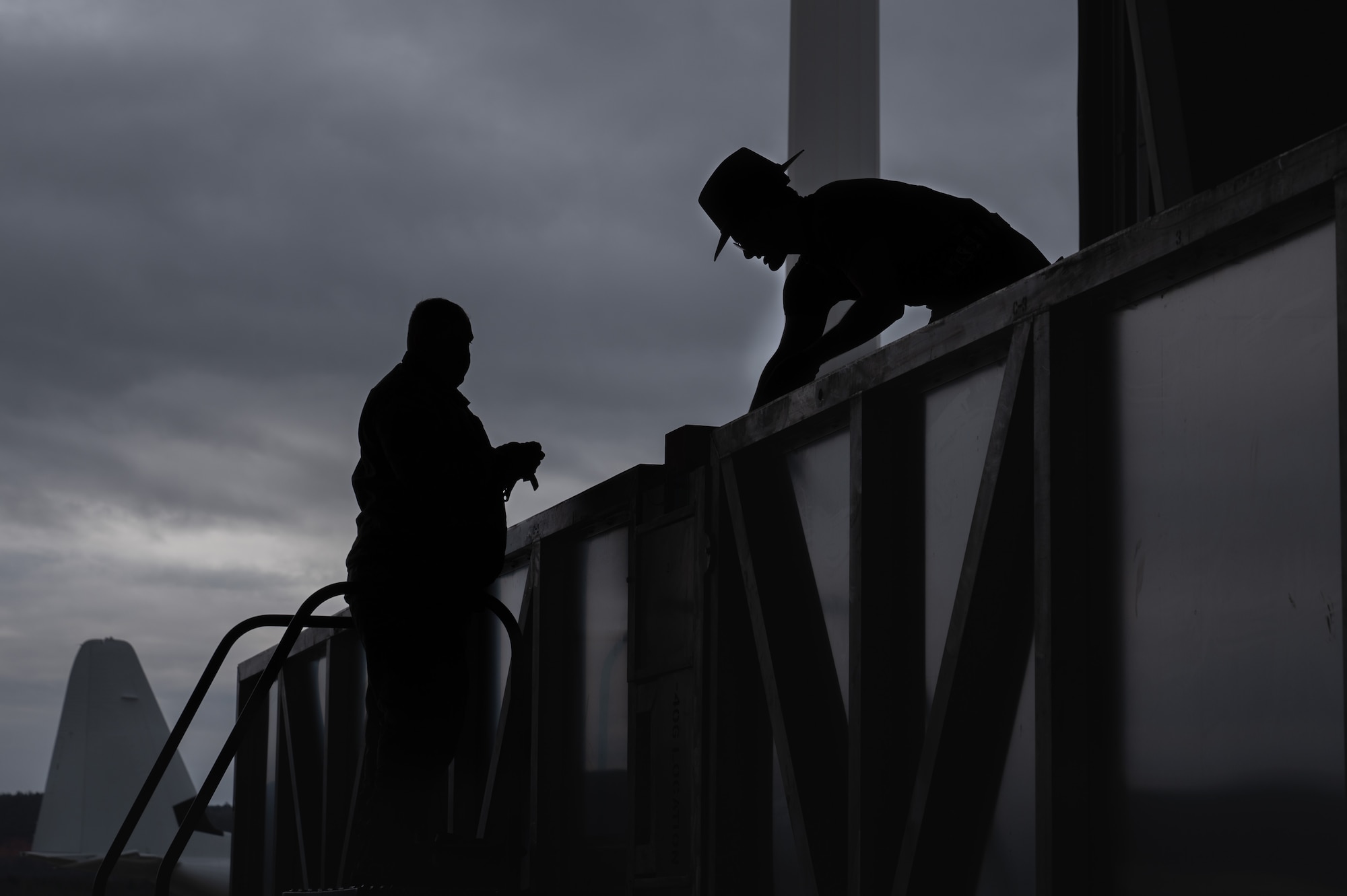 Two men work on opening a crate