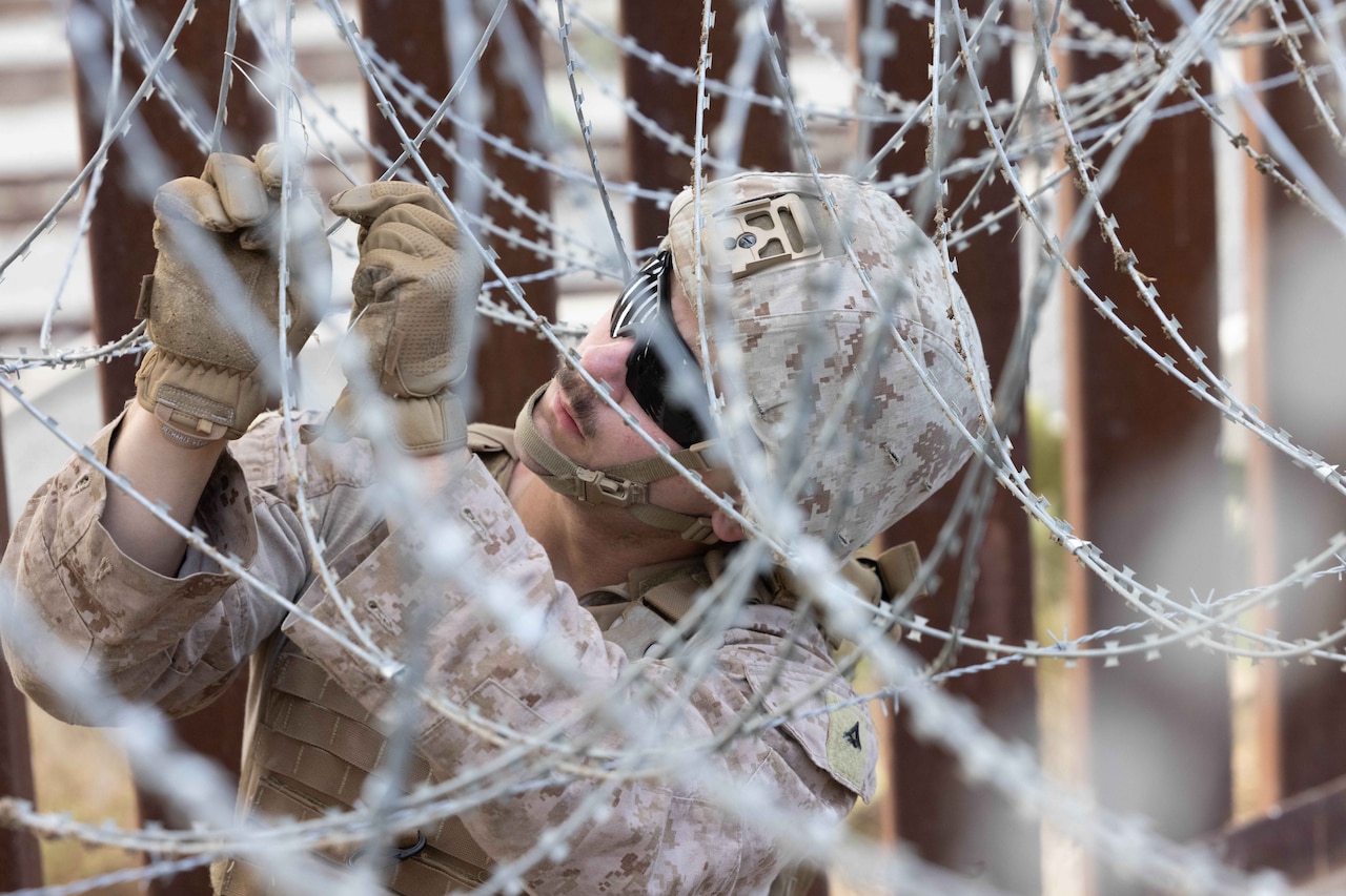 A Marine secures wired fencing.