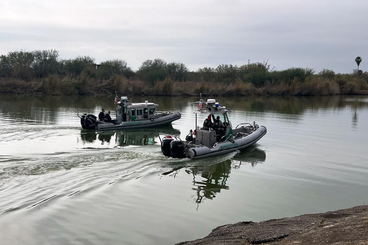 Two border patrol boats navigate a body of water.