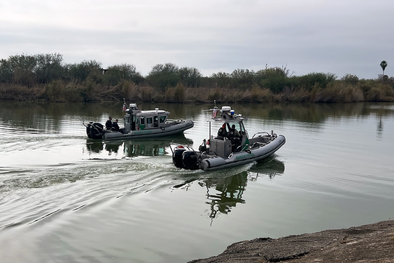 Two border patrol boats navigate a body of water.